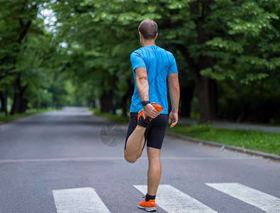 男跑步者早上训练前热身伸展健康的男跑步者早上训练前城市公园热身伸展图片