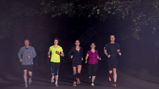 跑步队参加夜间训练群健康的人城市公园慢跑,跑步队夜间训练图片