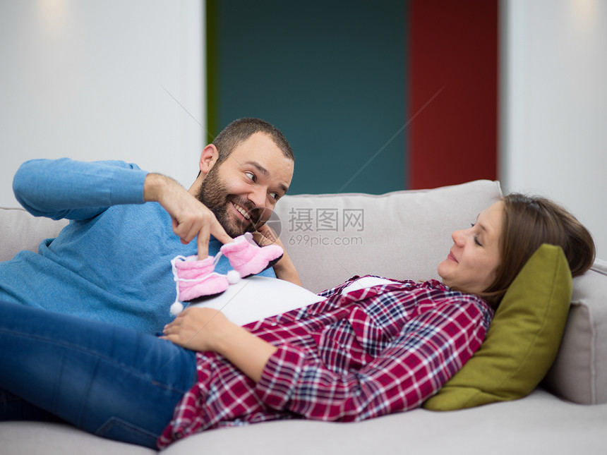 轻的怀孕夫妇沙发上放松幸福的怀孕夫妇家里的沙发上放松图片