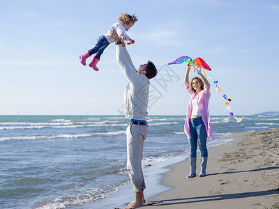家庭与小女儿休息玩风筝海滩秋天的天快乐的家庭秋天享受祝福图片