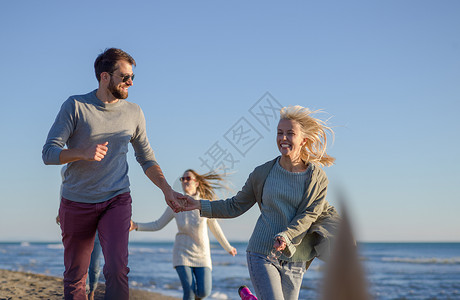 群轻的朋友秋天的日子里海滩上跑步秋天的群朋友海滩上跑步图片