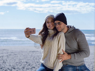 非常高兴的相爱的夫妇Autmun日的海滩上自拍漂亮的夫妇拍自拍照片背景图片