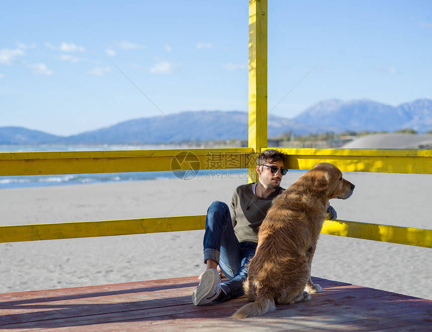 带着狗的男人秋天的海滩上享受空闲时间带狗的男人海滩上享受空闲时间图片
