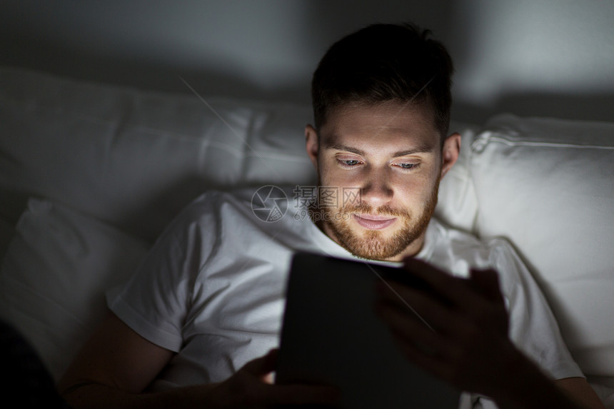 技术互联网通信人的轻人晚上家里卧室的床上用平板电脑轻人家里卧室的床上平板电脑图片