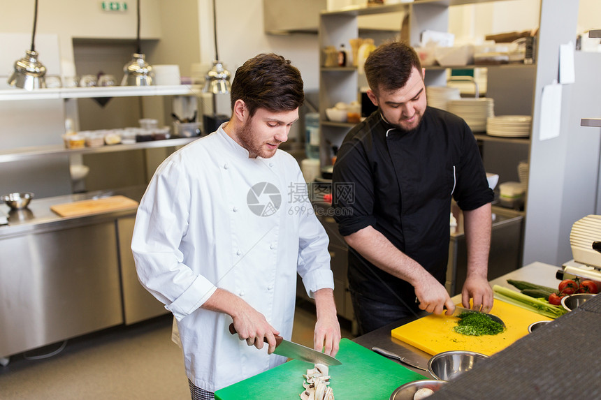 烹饪食物,职业人的快乐的男厨师,并餐厅厨房的砧板上用刀子切香槟蔬菜饭厨师烹饪食物餐厅厨房图片
