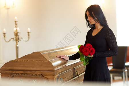 玫瑰城幸葬礼,人们哀悼的幸的女人带着红玫瑰棺材教堂的葬礼上葬礼上带着红玫瑰棺材的悲伤女人背景