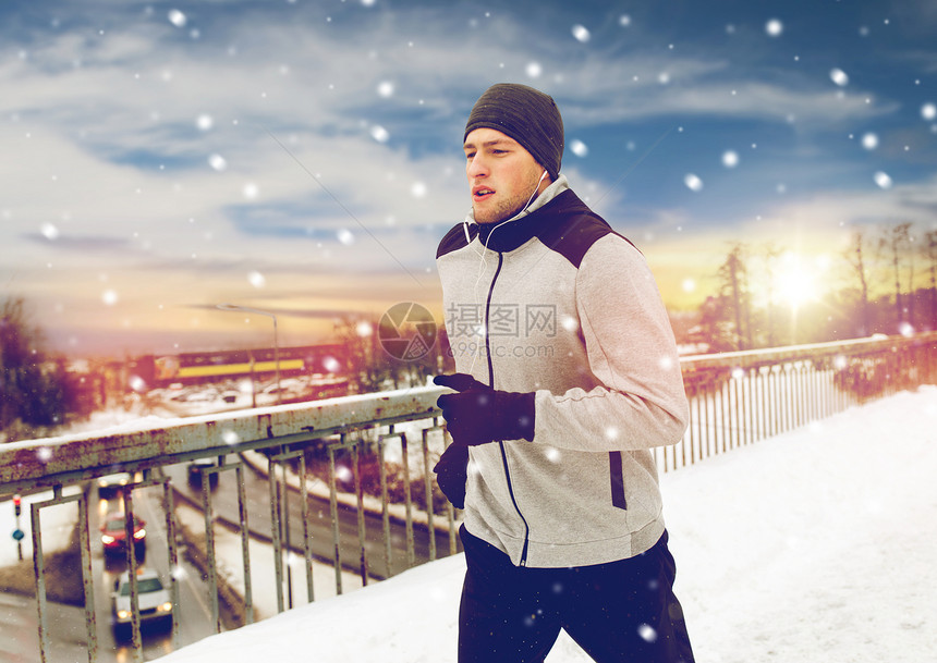 健身,运动,人,音乐健康的生活方式轻人戴着耳机沿着雪覆盖的冬季桥梁跑步戴耳机的人沿着冬桥跑图片