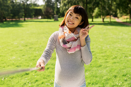 怀孕,人技术快乐的怀孕亚洲妇女与自拍棒公园拍照快乐的亚洲孕妇公园自拍图片
