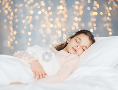 人,孩子,休息舒适的女孩睡床上的假日灯光背景女孩睡床上的假日灯图片