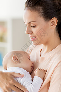家庭,母亲人的亲密的母亲抱着熟睡的小男孩家里紧紧抱着熟睡的婴儿的母亲图片