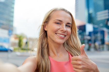 生活方式人们的快乐的轻女人城市街道上自拍,竖大拇指快乐的轻女人城市街头自拍背景图片
