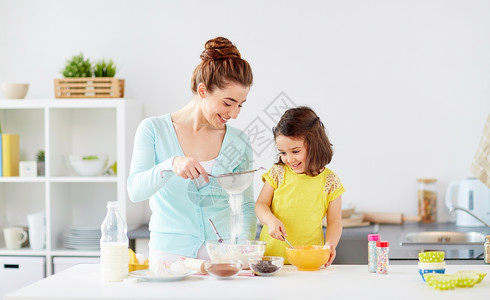 家庭,烹饪,烘焙人们的快乐的母亲小女儿用筛子筛粉家里厨房快乐的母女家烘焙背景图片