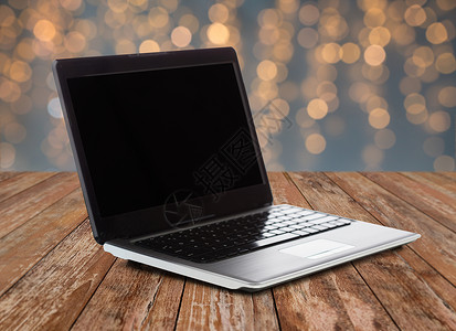 技术广告笔记本电脑与空白黑屏木制桌子上的诞灯背景笔记本电脑上空白的黑色屏幕背景图片