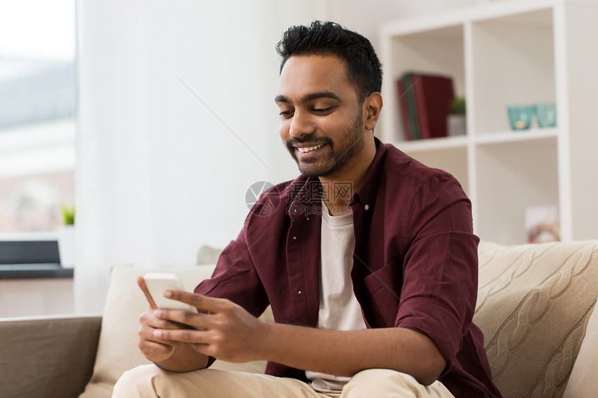 技术,互联网,通信人的快乐的微笑男人家里的智能手机短信家里智能手机的快乐男人图片