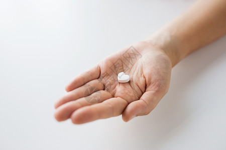 药物,营养补充剂人的近距离的手药丸的形状的心脏紧紧握住药心丸的手图片