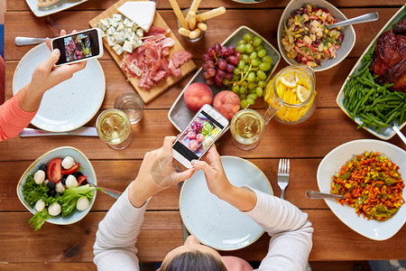 饮食,人技术智能手机的人桌子上拍摄食物人们用智能手机拍摄食物图片