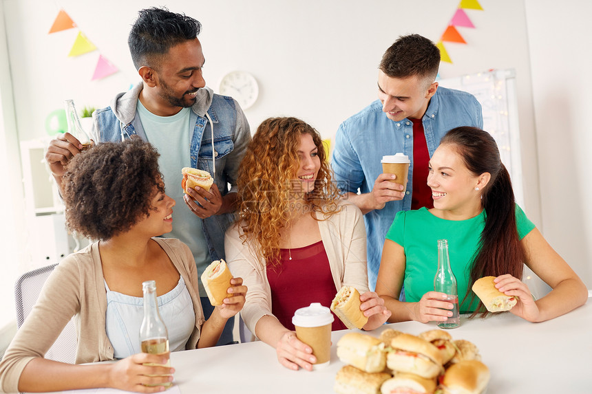 公司,庆祝人的快乐的朋友队吃三明治与咖啡非酒精饮料办公室聚会快乐的朋友队办公室聚会上吃饭图片