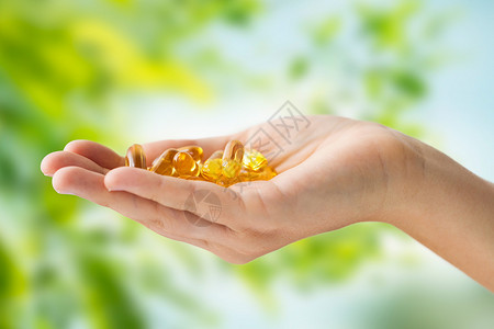 药物,营养补充剂人的密切手鱼肝油胶囊绿色的自然背景手鱼肝油胶囊图片