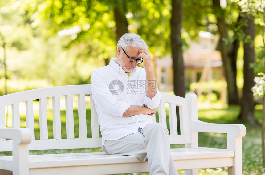 老,退休人们的体贴的老人戴着眼镜,坐夏季公园的长凳上夏天公园思想的老人图片