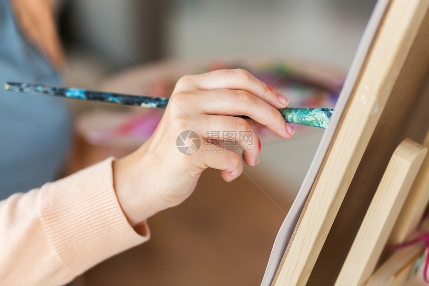 艺术创造力人的工作室用画笔画架画纸上的艺术家手的特写艺术家艺术工作室用画笔绘画的手图片