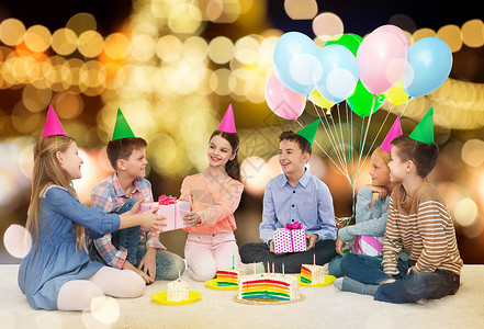 运动会上男孩童,节日,庆祝,友谊人的快乐的微笑孩子派帽子与蛋糕送礼物生日聚会上的节日灯光背景快乐的孩子生日聚会上送礼物背景