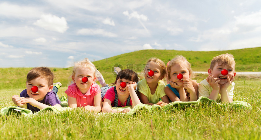 红鼻子日,慈善童的群快乐的孩子,小丑鼻子躺毯子上草地上快乐的孩子们躺草地上,红鼻子的日子图片