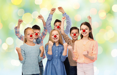 红鼻子日,慈善童的快乐的儿童朋友与小丑鼻子举拳头,庆祝胜利的绿灯背景红鼻子日快乐的孩子背景图片