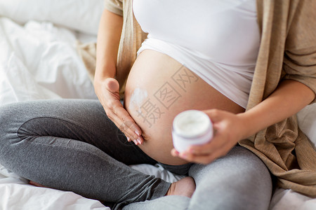 怀孕,人产妇的密切孕妇应用拉伸标记奶油腹部孕妇应用奶油腹部图片