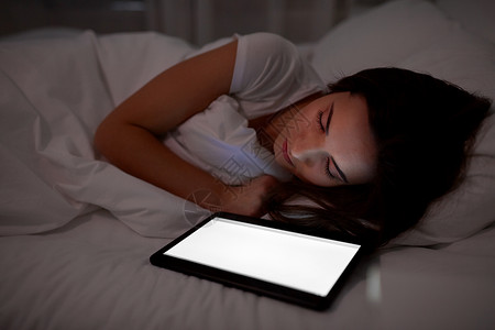 技术人的轻的妇女与平板电脑电脑睡觉家里晚上平板电脑的女人晚上睡床上图片