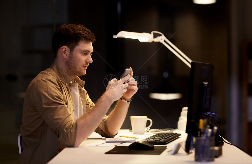 商业,截止日期技术男人与智能手机电脑工作夜间办公室智能手机的男人深夜办公室工作图片