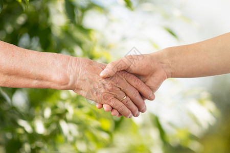 人龄家庭支持亲密的老妇女轻妇女牵手绿色的自然背景亲密的老人轻的女人牵手背景图片