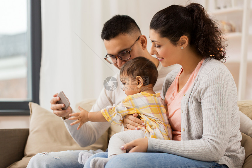 家庭,父母人的快乐的母亲,父亲婴儿女儿与智能手机家里母亲,父亲婴儿家里智能手机图片