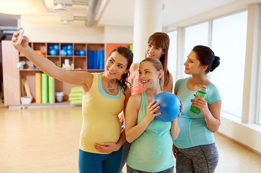 怀孕,健身健康的生活方式群快乐的孕妇健身房用智能手机自拍孕妇健身房用智能手机自拍图片