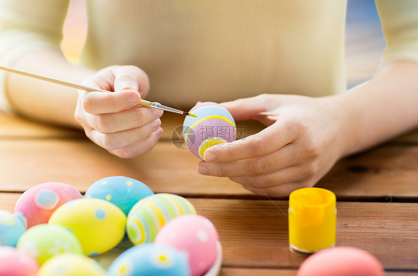 复活节,假日,传统人们的密切妇女的手着色鸡蛋与颜色刷子木制桌子靠近女人的手着色复活节彩蛋图片