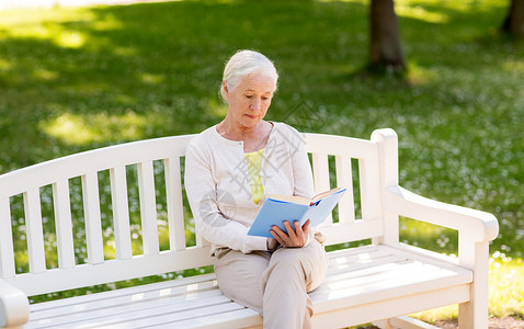 老,退休人的老妇女阅读书籍坐长凳上的夏季公园暑期公园的高级女读书图片