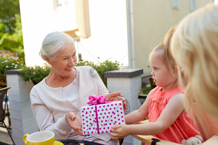 家庭世代人的孙女咖啡馆餐馆给快乐的祖母送礼物孙女给祖母送礼物图片
