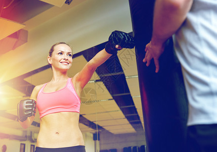 运动,健身,生活方式人的微笑的女人与私人教练拳击袋健身房微笑的女人私人教练拳击健身房图片