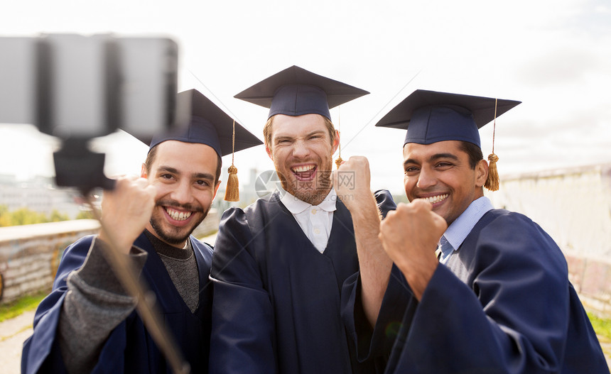 教育毕业技术成就群快乐的国际学生穿着灰浆板学士服户外自拍棒拍照庆祝快乐的男学生毕业生自拍图片