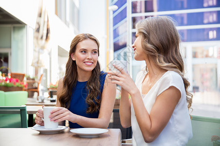 沟通友谊的微笑的轻妇女街头咖啡馆喝咖啡微笑的轻女人街头咖啡馆喝咖啡图片