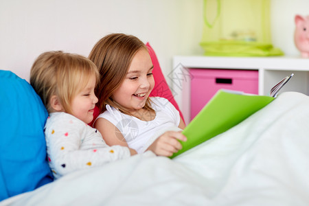 童休闲家庭观念小女孩姐妹床上看书小女孩姐妹床上看书图片