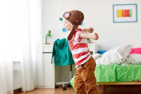 童,想象梦想的快乐的小男孩飞行员帽子玩游戏家快乐的小男孩戴着领航帽家玩图片