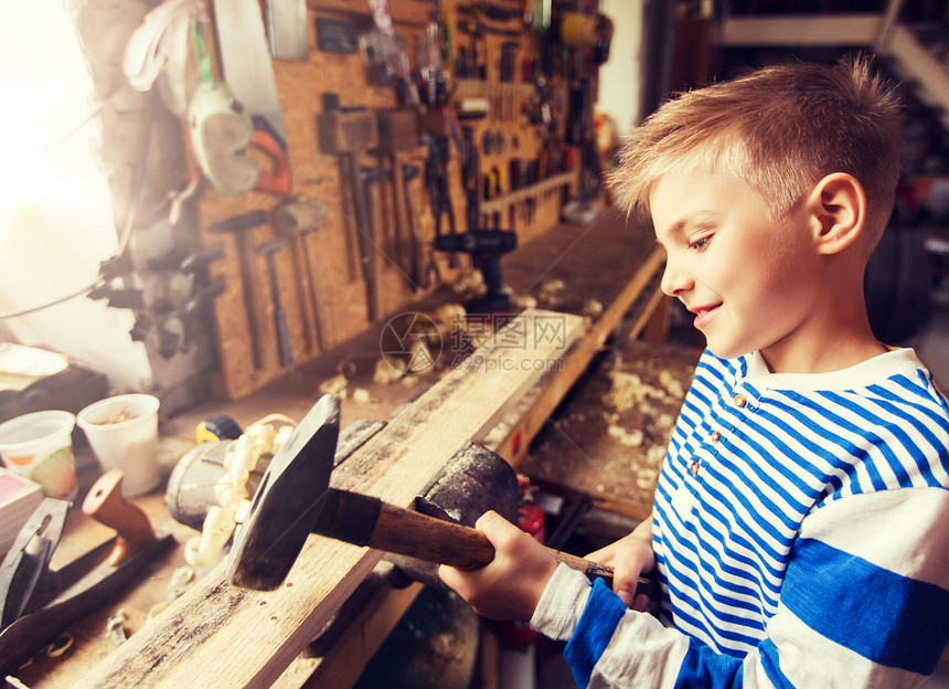 木工,建筑人的快乐的小男孩用锤击木板车间快乐的小男孩车间用木板快乐的小男孩车间用木板图片