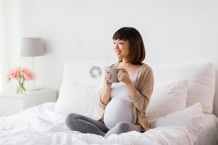 怀孕,休息,人期望的快乐的亚洲孕妇家里的卧室床上喝茶快乐的孕妇家里喝杯茶快乐的孕妇家里喝杯茶图片