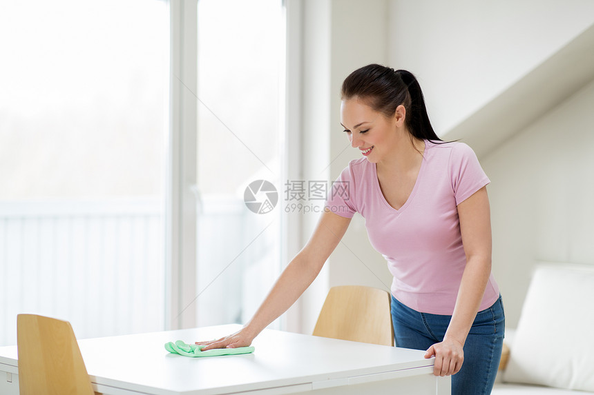 家庭,清洁人的快乐的女人家庭主妇擦拭桌子与微纤维布家里女人家里用微纤维布清洗桌子女人家里用微纤维布清洗桌图片
