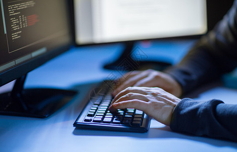 坐着用计算机电脑在键盘上打字编写代码程序工作的男人图片