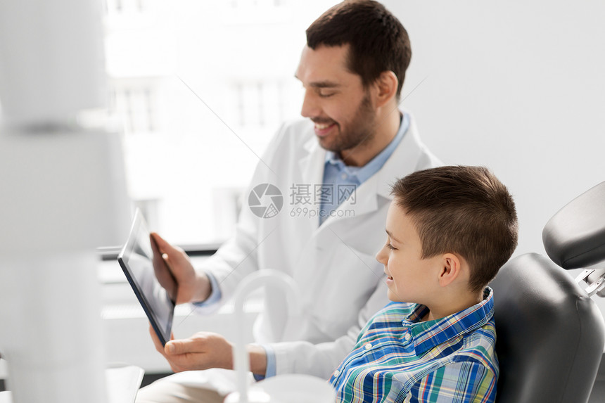 医学,牙科医疗微笑的男牙医向牙科诊所的儿童病人展示平板电脑牙医诊所向儿童病人展示平板电脑牙医诊所向儿童病人图片