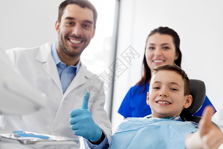 口腔科医生牙医与儿童病人在牙科诊所竖起大拇指背景