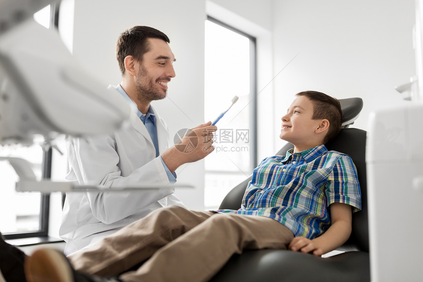 医学,牙科保健男牙医牙科诊所向儿童病人展示牙刷牙医带牙刷,儿童病人诊所牙医带牙刷,儿童病人诊所图片