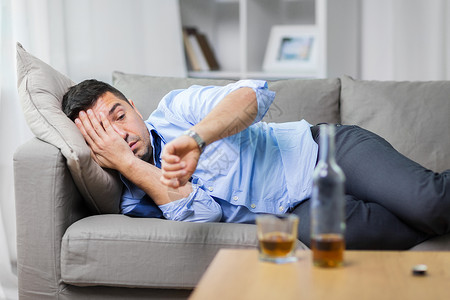 费雷敦沙尔酗酒,酗酒人的男酗酒者躺沙发上看手表酒鬼躺沙发上看着手表酒鬼躺沙发上看着手表背景