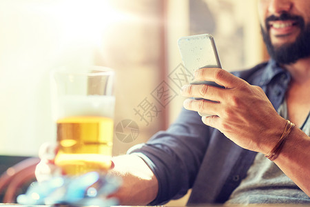 人,休闲技术近距离的人与智能手机喝啤酒阅读信息酒吧酒吧酒吧用智能手机啤酒接近男人酒吧用智能手机啤酒背景图片